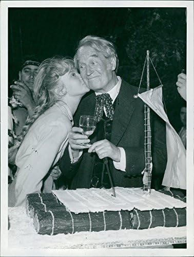 תצלום וינטג 'של מוריס שבלייה במסיבה ואישה שמתנשקת על לחיו.